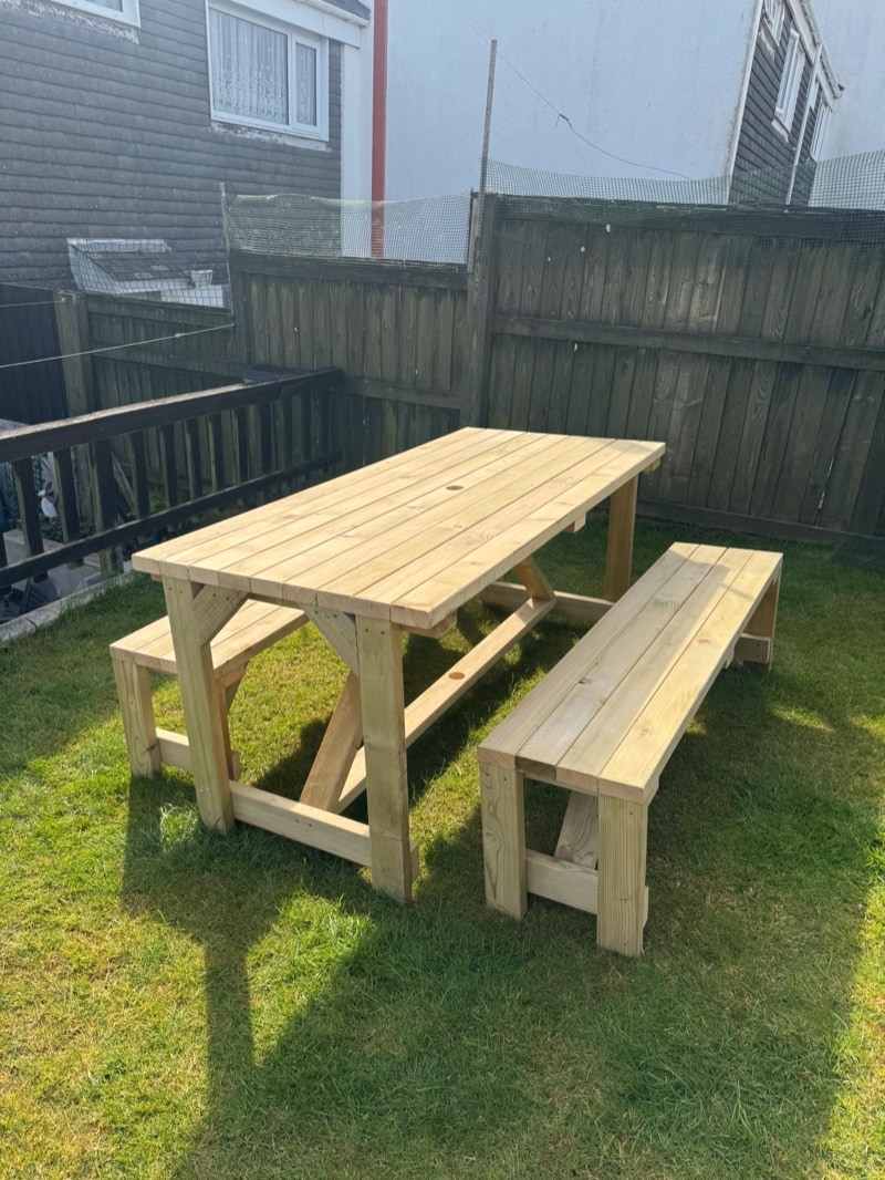 A heavy timber table with two benches standing on a lawn