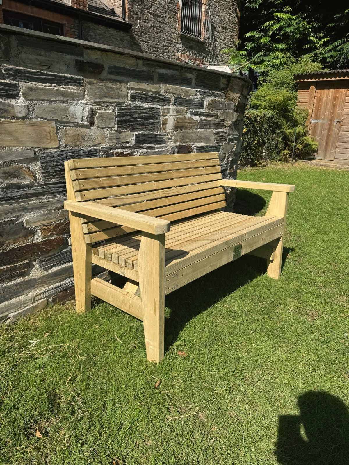 A 4ft slated timber bench for two on a lawn