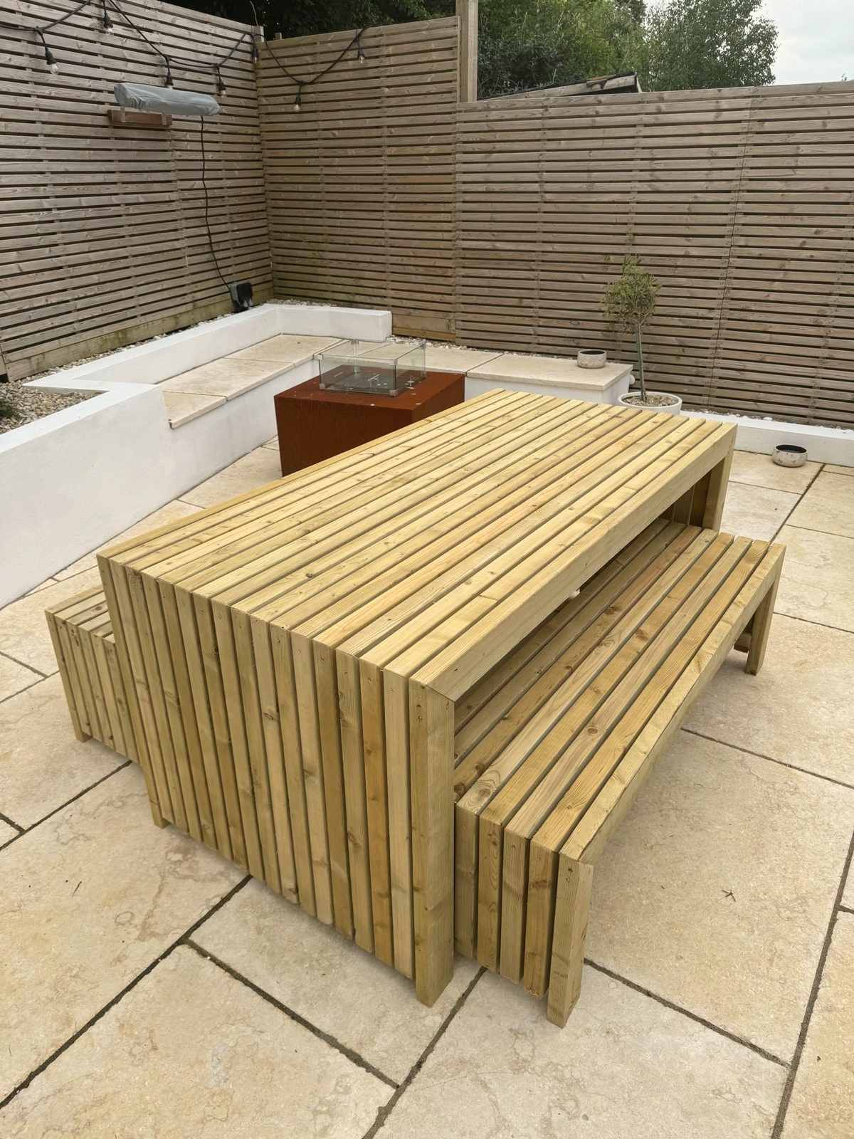 A slated six-seater table and benches set on a patio