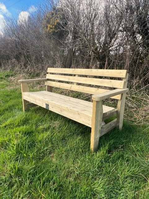 The 6ft Garden Bench with an arched seat and slatted back, on long grass