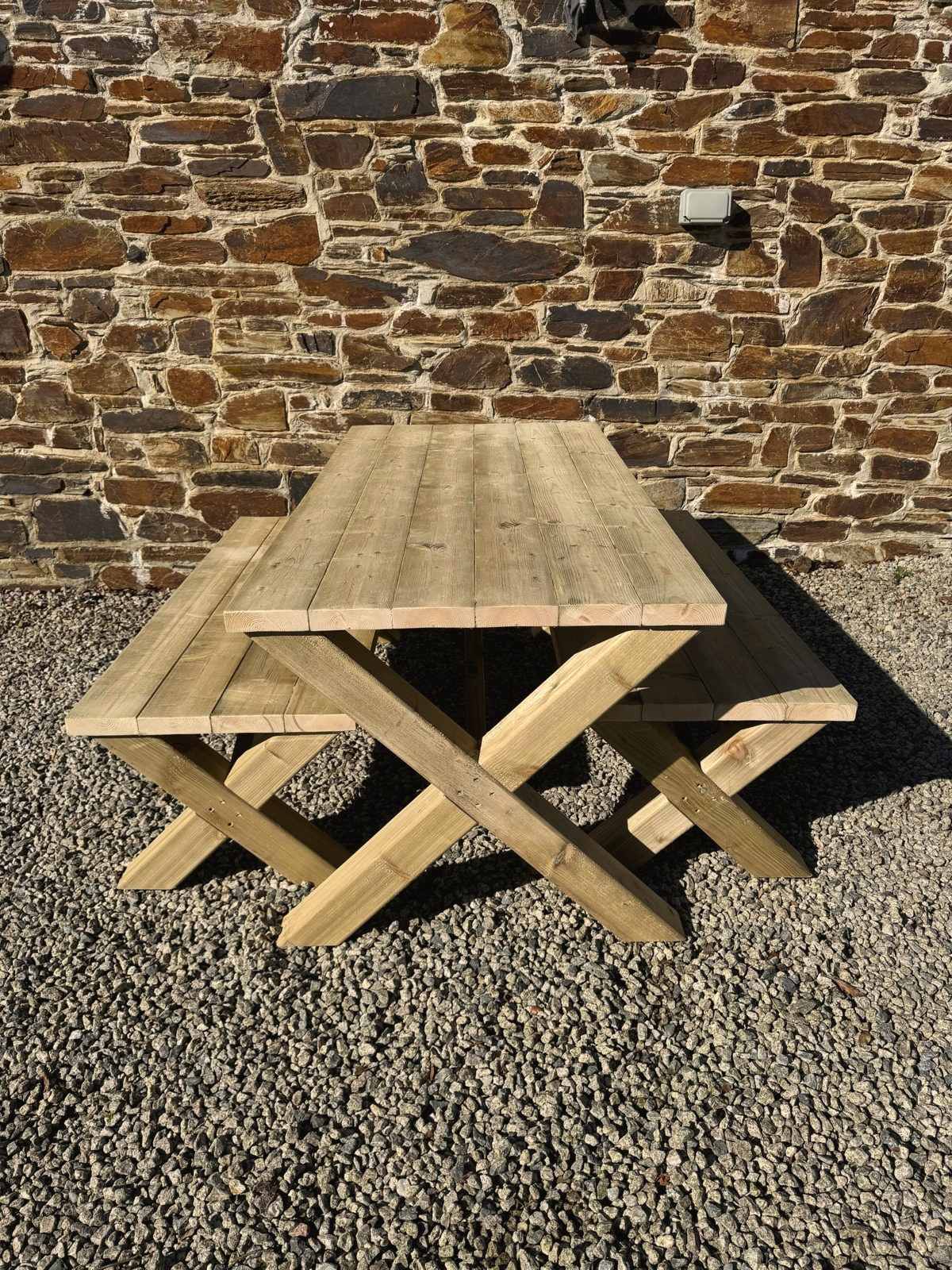 A cross-leg X table with two benches on gravel