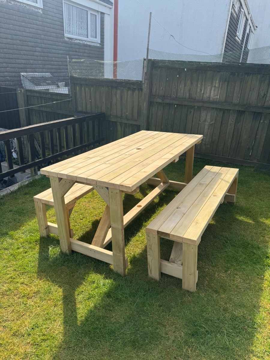 A heavy timber table with two benches on a lawn