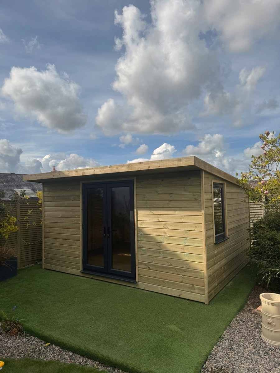 A pent-roof garden room with dark-framed glazed doors on artificial grass
