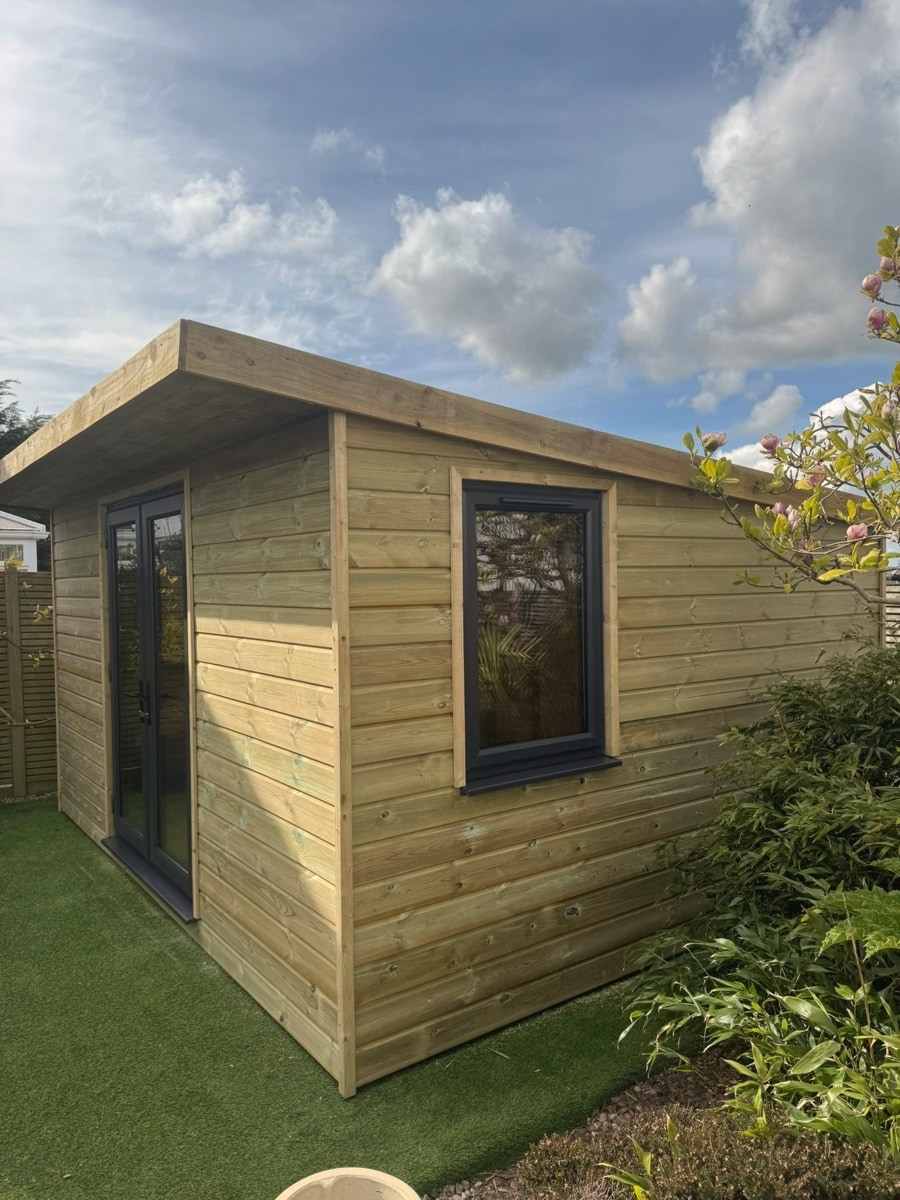A garden room with glazed doors and a side window among shrubs