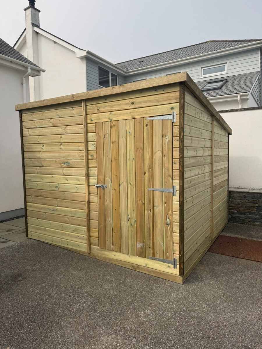 A pent-roof shed with double doors on a tarmac drive
